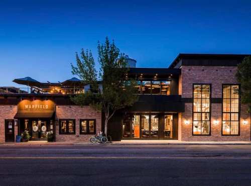 Exterior view of the Warfield building at dusk, featuring large windows and outdoor seating.