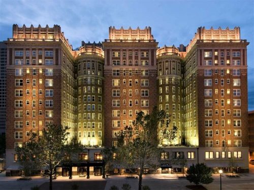 Historic brick hotel with illuminated architecture, featuring multiple stories and decorative details, set against a twilight sky.