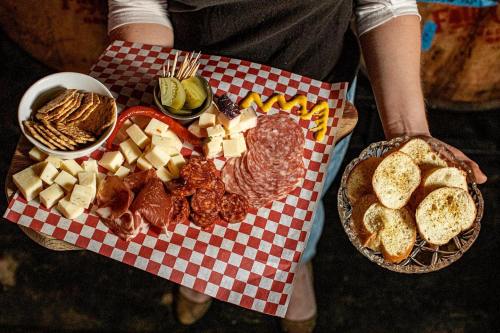 A wooden board with assorted cheeses, meats, crackers, pickles, and mustard, alongside a plate of toasted bread.