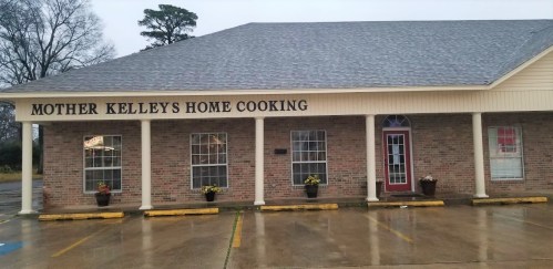 Exterior of a restaurant named "Mother Kelley's Home Cooking," featuring a brick facade and flower pots by the entrance.