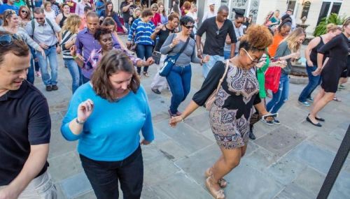 A diverse group of people dancing together outdoors, enjoying a lively social event.