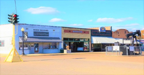 A small town street featuring historic buildings, shops, and a traffic light under a clear blue sky.