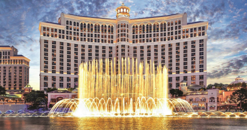 The Bellagio Hotel with its iconic fountain show, illuminated against a twilight sky.