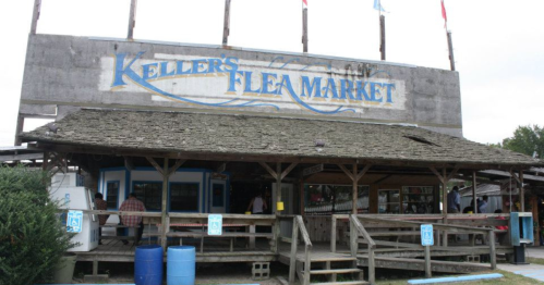 Exterior of Keller's Flea Market, featuring a wooden structure with a sign and outdoor seating area.