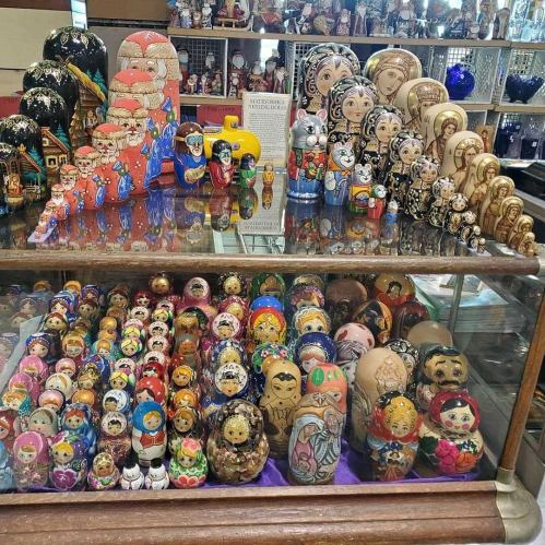 A display of colorful Russian nesting dolls, featuring various designs and sizes, arranged in a glass case.