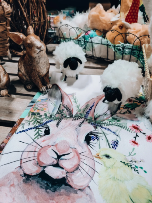 A colorful table display featuring a rabbit illustration, sheep figurines, and decorative spring elements.