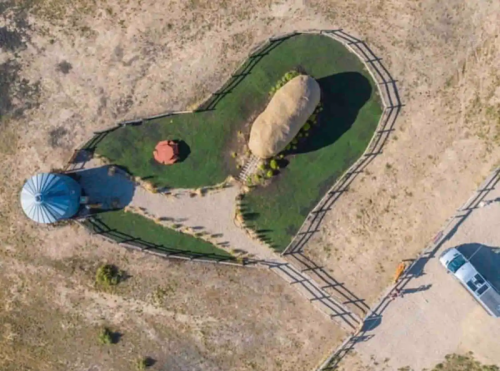 Aerial view of a heart-shaped garden with a rock centerpiece, surrounded by a fence and a gazebo.