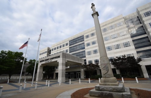 Exterior view of the Gordon County Courthouse, featuring a flagpole and a monument in front of a modern building.