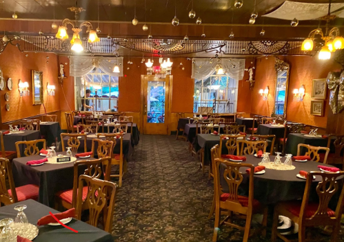 Cozy restaurant interior with dark tables, elegant decor, and warm lighting, creating an inviting atmosphere.
