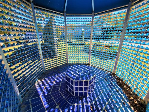 A circular structure with blue tiles and a patterned floor, surrounded by a lattice of blue and white elements.