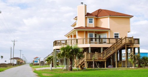A peach-colored beach house along a paved pathway in Holly Beach, Louisiana