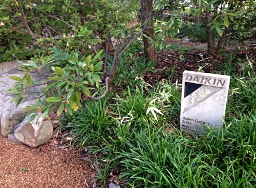 A stone plaque in a garden reads "DAIKIN, Daikin's Garden, 2003," surrounded by greenery and rocks.