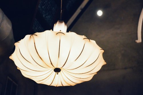 A decorative pendant light with a scalloped design, illuminating a dimly lit room with a soft glow.