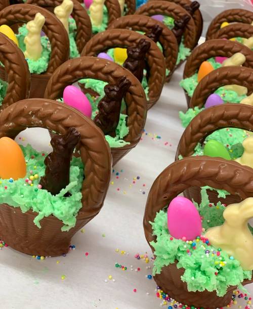 Chocolate Easter baskets filled with colorful eggs and bunnies, surrounded by green coconut "grass" and sprinkles.