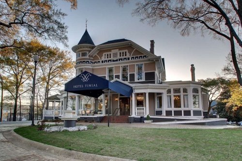 Historic Hotel Finial with a grand facade, porch, and landscaped grounds, set against a clear sky.