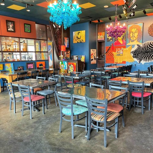 Colorful restaurant interior with artistic decor, vibrant chandeliers, and tables set for dining.