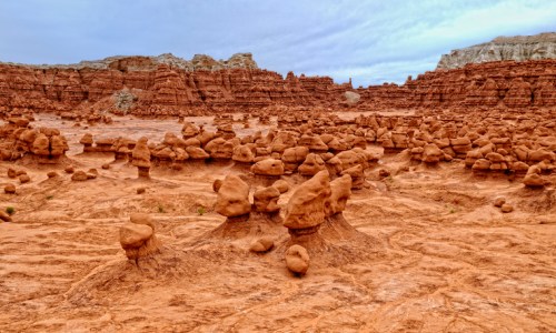 A vast desert landscape featuring unique rock formations resembling mushrooms against a cloudy sky.