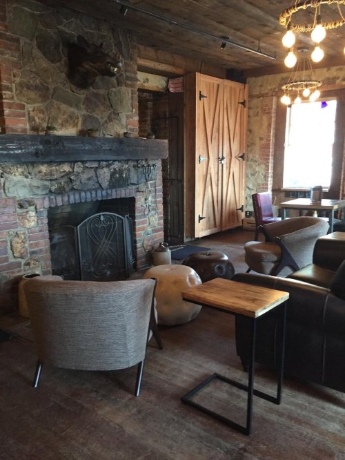 Cozy interior with a stone fireplace, wooden accents, and comfortable seating in a rustic setting.