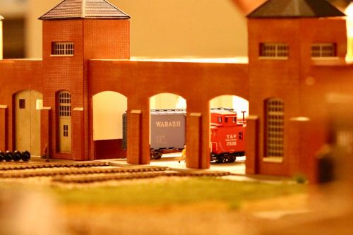 A model train station with red brick buildings and a small red train next to a blue freight car.