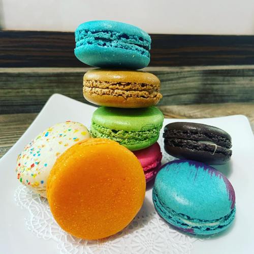 A colorful assortment of macarons stacked on a white plate, featuring various flavors and vibrant colors.