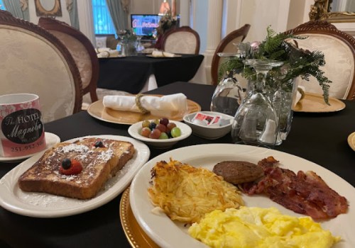 A breakfast plate with French toast, eggs, bacon, sausage, and hash browns, set on a dining table with elegant decor.
