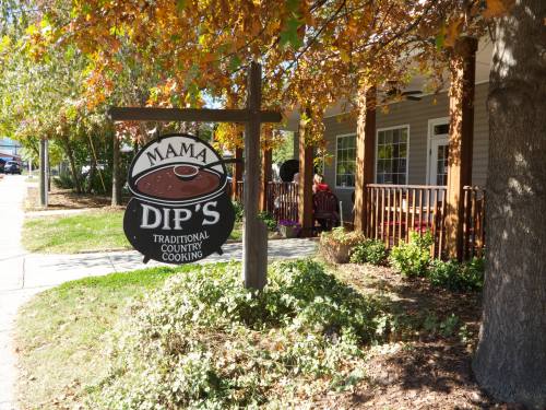 Sign for Mama Dip's, a restaurant featuring traditional country cooking, surrounded by autumn foliage.