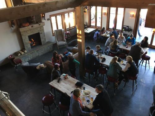 A cozy restaurant interior with a fireplace, featuring groups of people dining and socializing at tables and the bar.