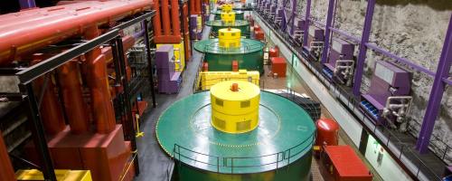 Colorful industrial machinery in a large underground facility, featuring large circular platforms and various equipment.