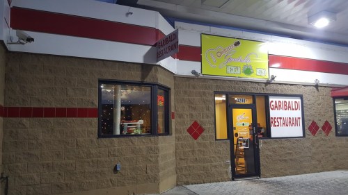 Exterior of Garibaldi Restaurant, featuring a bright sign and large windows, located in a commercial building.