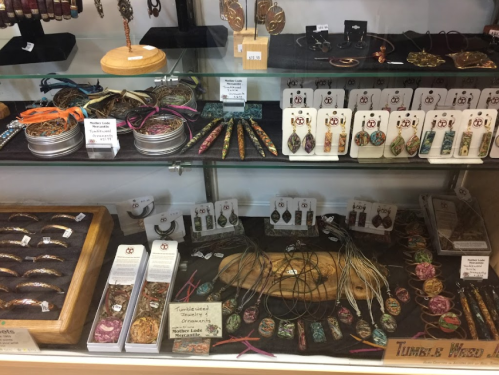 Display case filled with various handmade jewelry pieces, including pendants, earrings, and decorative items.