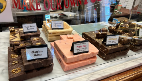 A display of various fudge flavors, including Peanut Butter Chocolate, Tiger Butter, and Prickly Pear, in a shop.