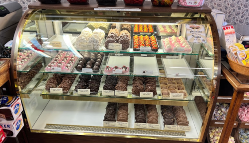 A display case filled with various colorful chocolates and confections, neatly arranged for customers.
