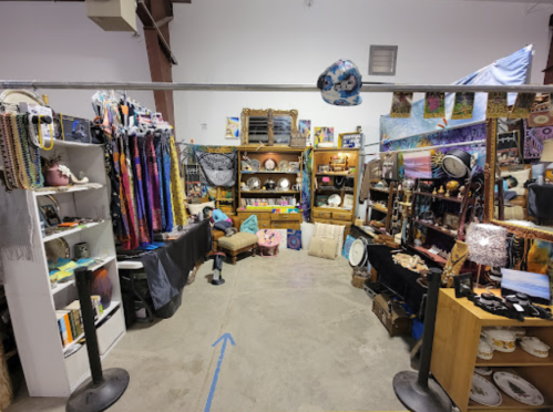 A vibrant marketplace with colorful textiles, art, and various handmade items displayed on shelves and tables.