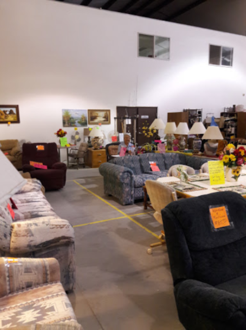 A spacious furniture store with various sofas, chairs, and tables, all marked with price tags and surrounded by decor.