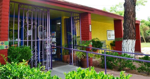 Colorful building entrance with purple gates, potted plants, and a ramp leading to the door.