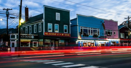 Downtown North Conway, NH at night with historic storefronts and cars driving by