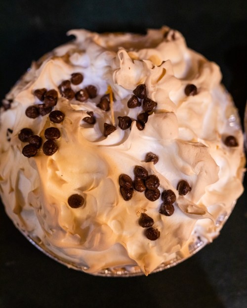 A close-up of a dessert topped with fluffy whipped cream and scattered chocolate chips.
