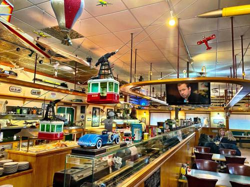 A cozy diner filled with vintage decor, model airplanes, and a large TV showing a man speaking.