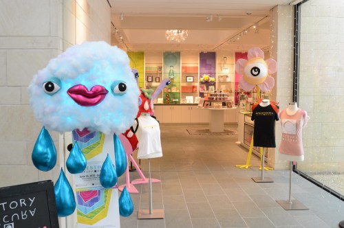Colorful display featuring whimsical character sculptures and clothing mannequins in a bright retail space.