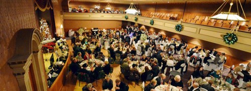 A festive banquet hall filled with guests dining at elegantly set tables, decorated for a celebration.