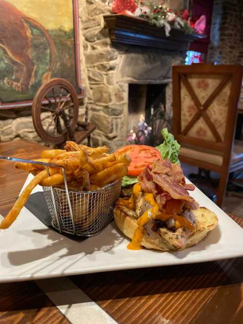 A delicious burger topped with bacon and cheese, served with a side of crispy fries in a basket, near a cozy fireplace.