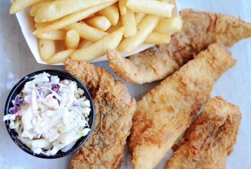 A plate featuring crispy fried fish fillets, a side of coleslaw, and golden French fries.