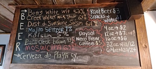 Chalkboard menu listing various beers with prices, including styles like stout, IPA, and seltzer.