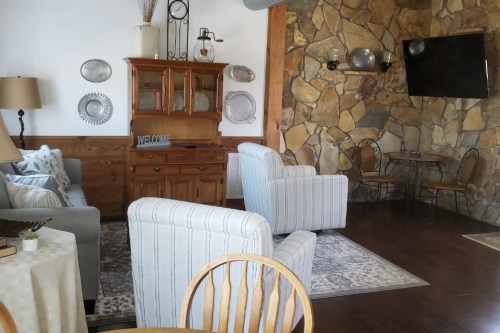 Cozy living area with stone wall, wooden furniture, and comfortable seating, creating a welcoming atmosphere.