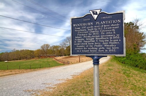 Historical marker for Woodburn Plantation in South Carolina, detailing its history and significance. Gravel road in background.