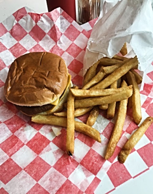 A burger on a checkered paper plate with a side of golden French fries.