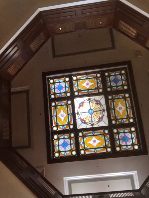 Stained glass ceiling with colorful geometric patterns, viewed from below in an octagonal space.