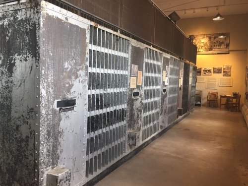 A row of old, weathered prison cells in a museum setting, showcasing historical incarceration.