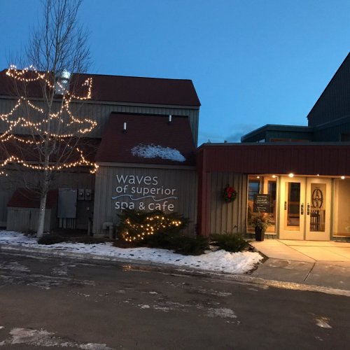 A cozy building with festive lights, snow on the ground, and a welcoming entrance.
