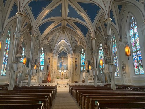 Interior of a grand church featuring ornate architecture, stained glass windows, and a central altar.